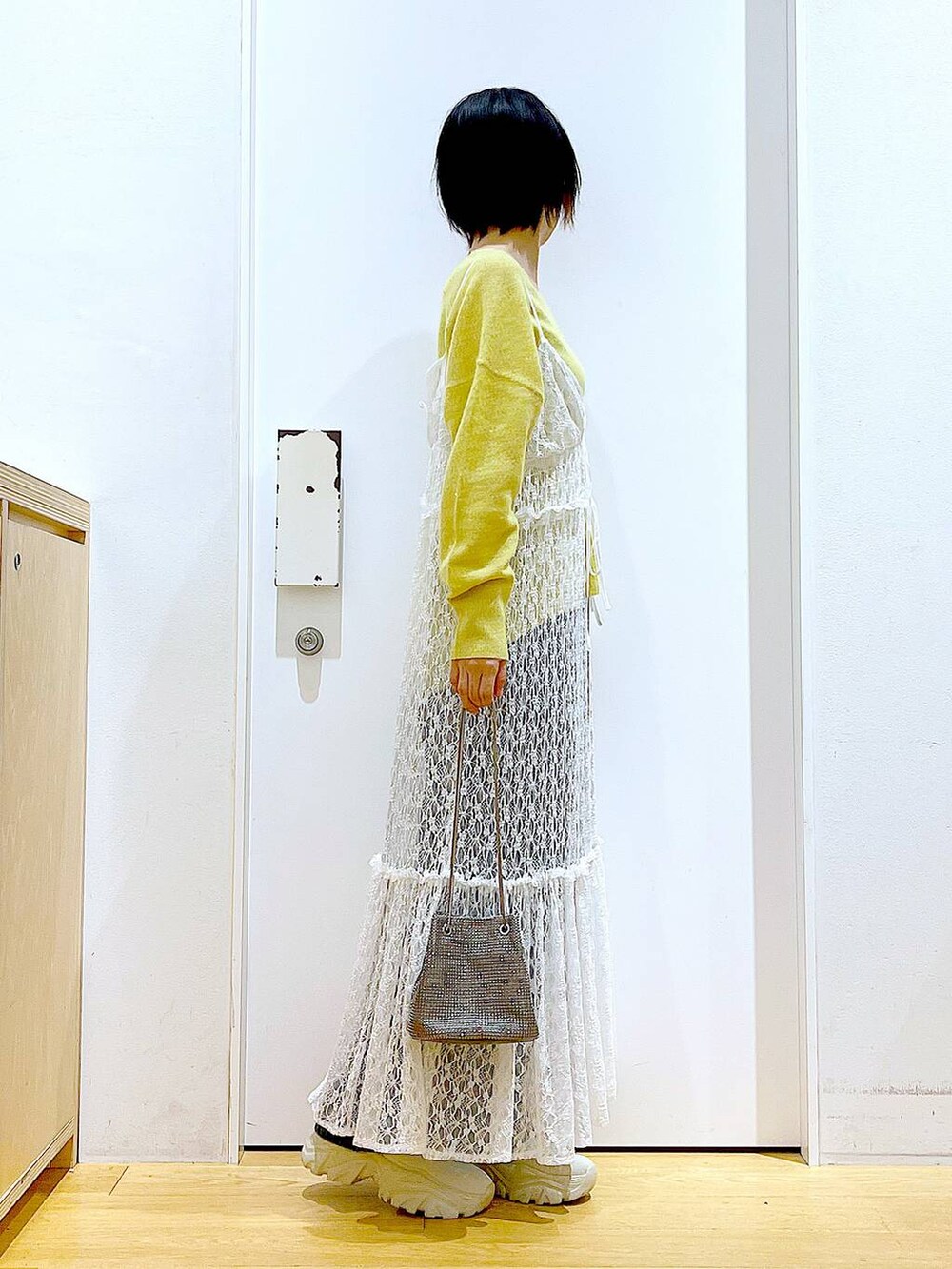 イエロー系のニット/セーター、グレー系のショルダーバッグ、ホワイト系のワンピースを着用したレディースの冬コーディネートの4枚目の写真