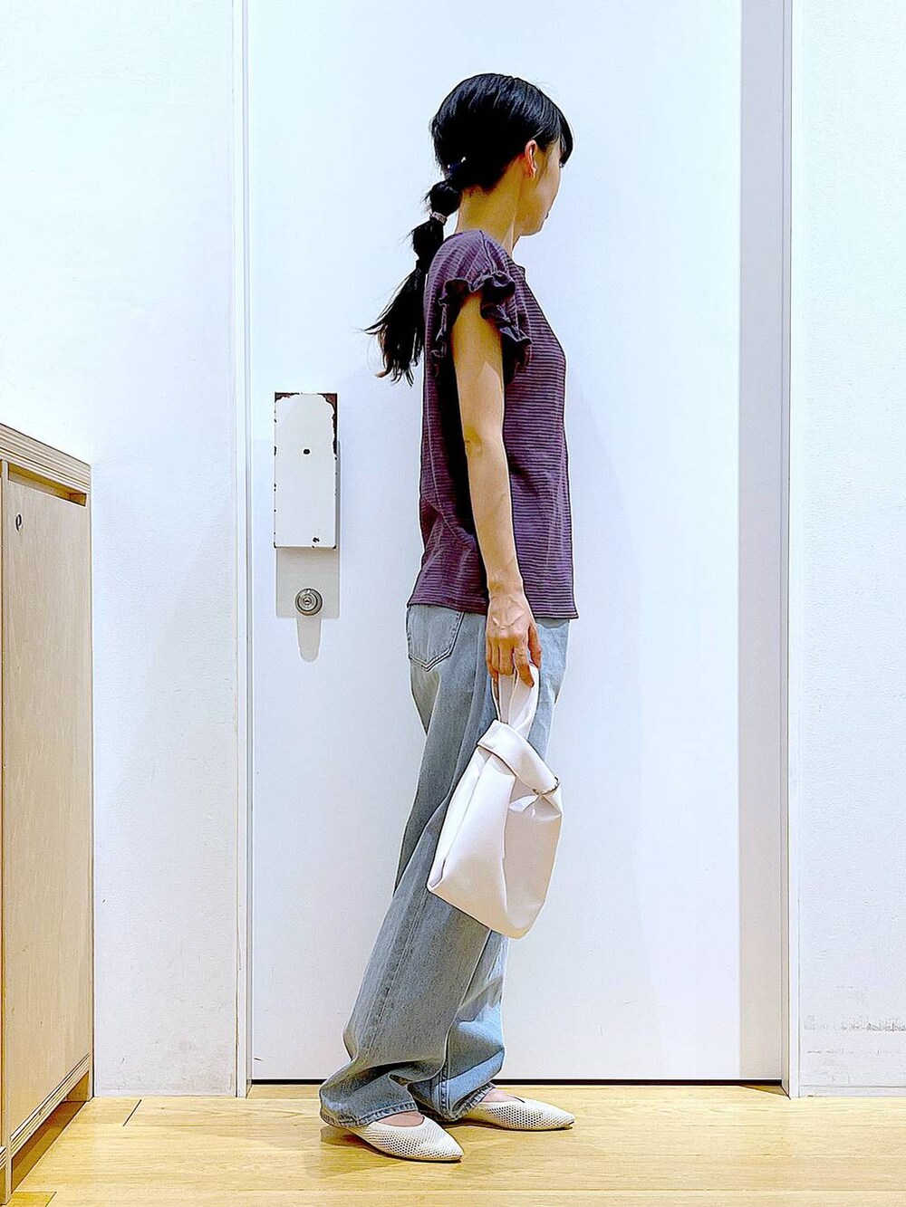 ホワイト系のショルダーバッグ、ブルー系のデニムパンツ、ホワイト系のパンプスを着用したレディースの春コーディネートの3枚目の写真