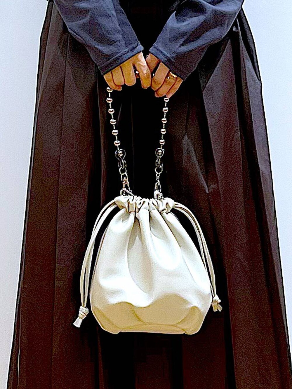 ベージュ系のショルダーバッグ、ホワイト系のパンプス、ブラック系のベストを着用したレディースの秋コーディネートの9枚目の写真