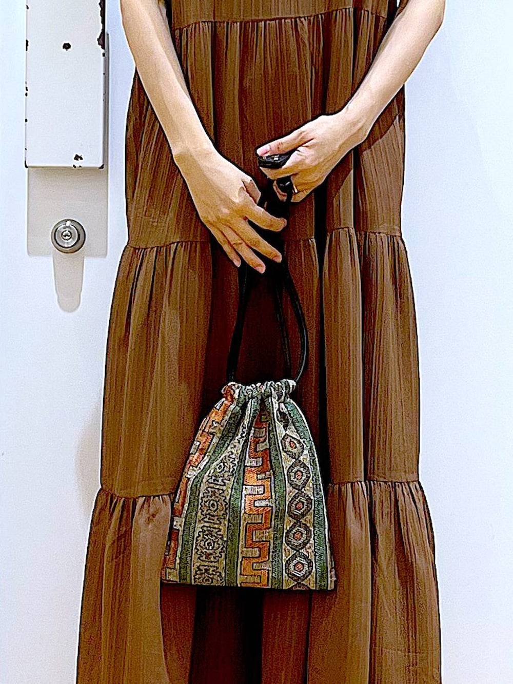 ブラウン系のショルダーバッグ、ブラック系のサンダル、グレー系のTシャツ/カットソーを着用したレディースの夏コーディネートの7枚目の写真