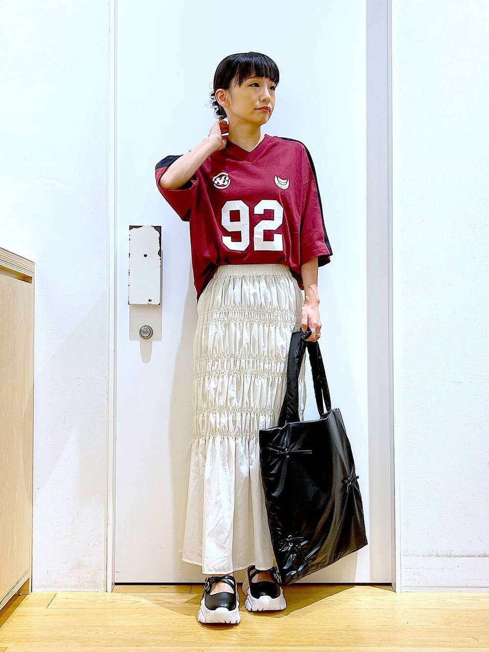 ホワイト系のスカート、ブラック系のスニーカー、ブラック系のトートバッグを着用したレディースの秋コーディネートの2枚目の写真