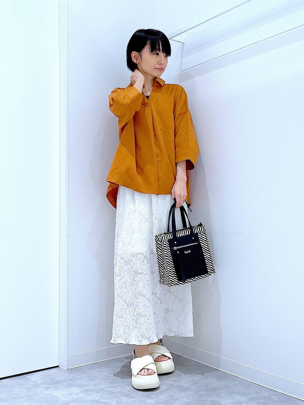 ブラック系のショルダーバッグ、ホワイト系のサンダル、ホワイト系のスカートを着用したレディースの夏コーディネートの2枚目の写真