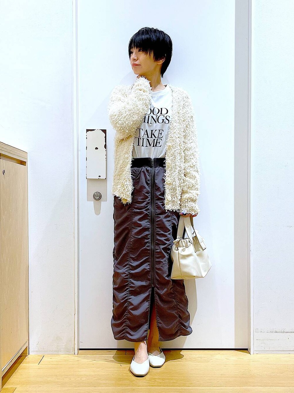 グレー系のスカート、ホワイト系のショルダーバッグ、ホワイト系のパンプスを着用したレディースの春コーディネートの2枚目の写真