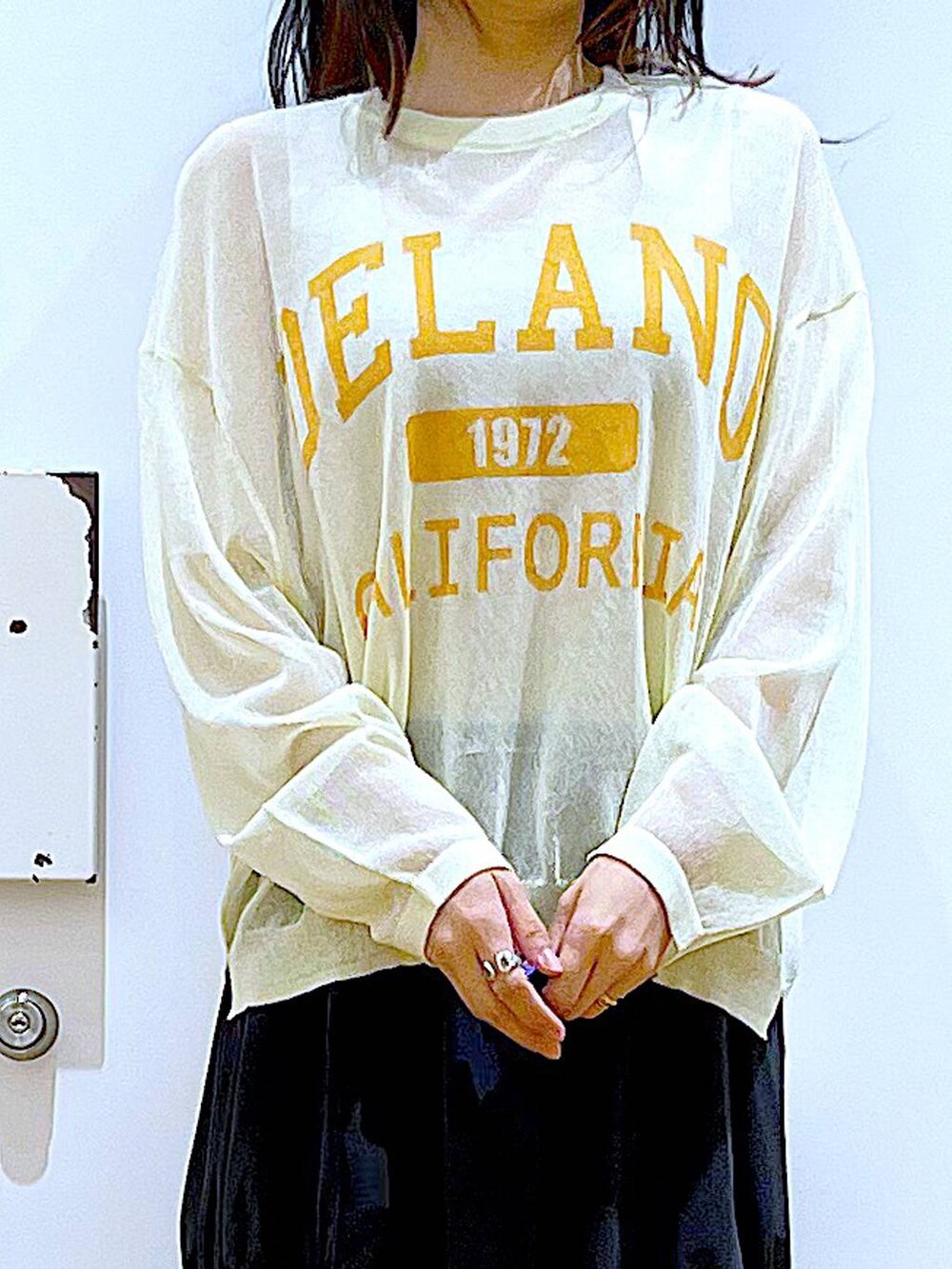 ホワイト系のニット/セーター、ブラック系のスカート、ブラック系のパンプスを着用したレディースの夏コーディネートの7枚目の写真