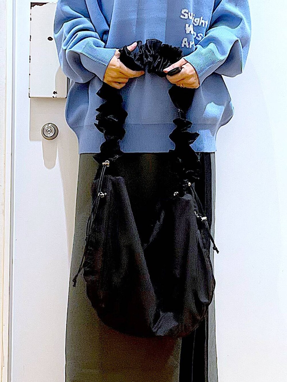 ブルー系のニット/セーター、ブラック系のショルダーバッグ、グレー系のスカートを着用したレディースの冬コーディネートの9枚目の写真