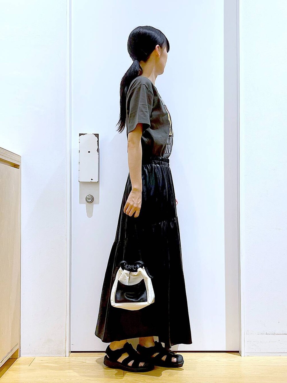 ホワイト系のショルダーバッグ、ブラック系のスリッポン、グレー系のTシャツ/カットソーを着用したレディースの夏コーディネートの4枚目の写真