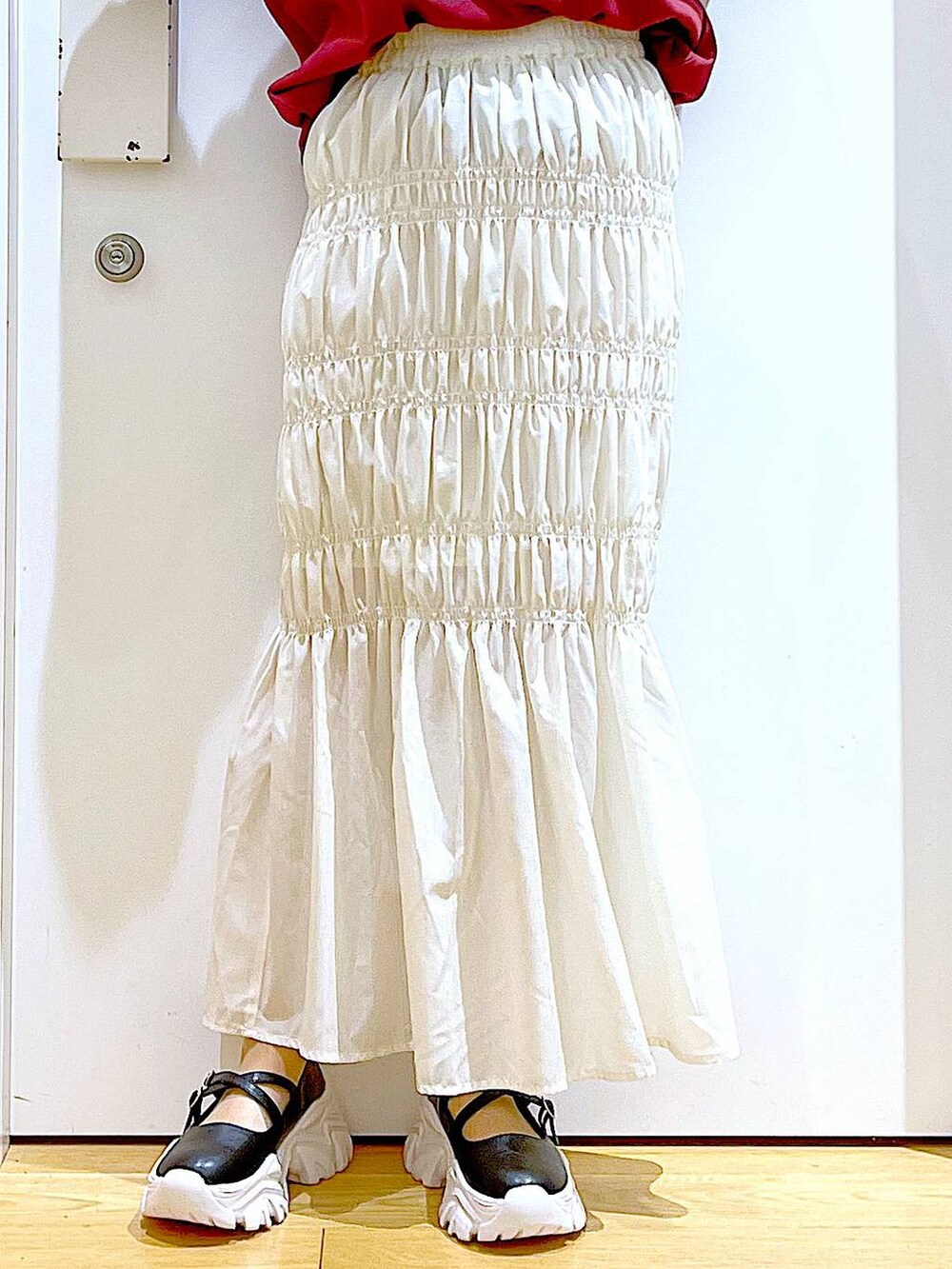 ホワイト系のスカート、ブラック系のスニーカー、ブラック系のトートバッグを着用したレディースの秋コーディネートの8枚目の写真