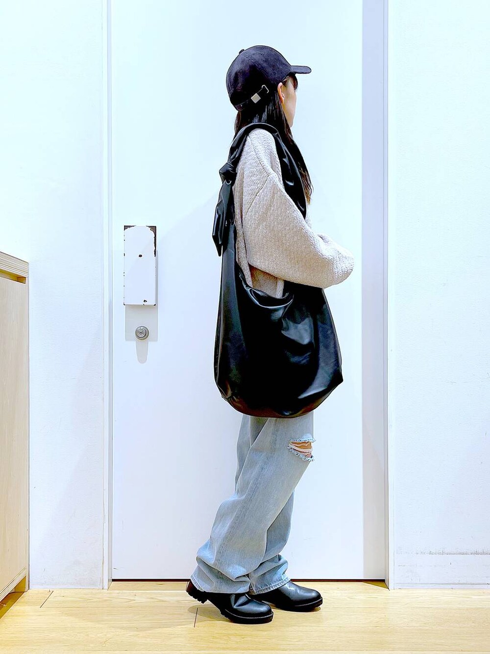 ホワイト系のニット/セーター、ブラック系のショルダーバッグ、ブラック系のブーツを着用したレディースの冬コーディネートの4枚目の写真