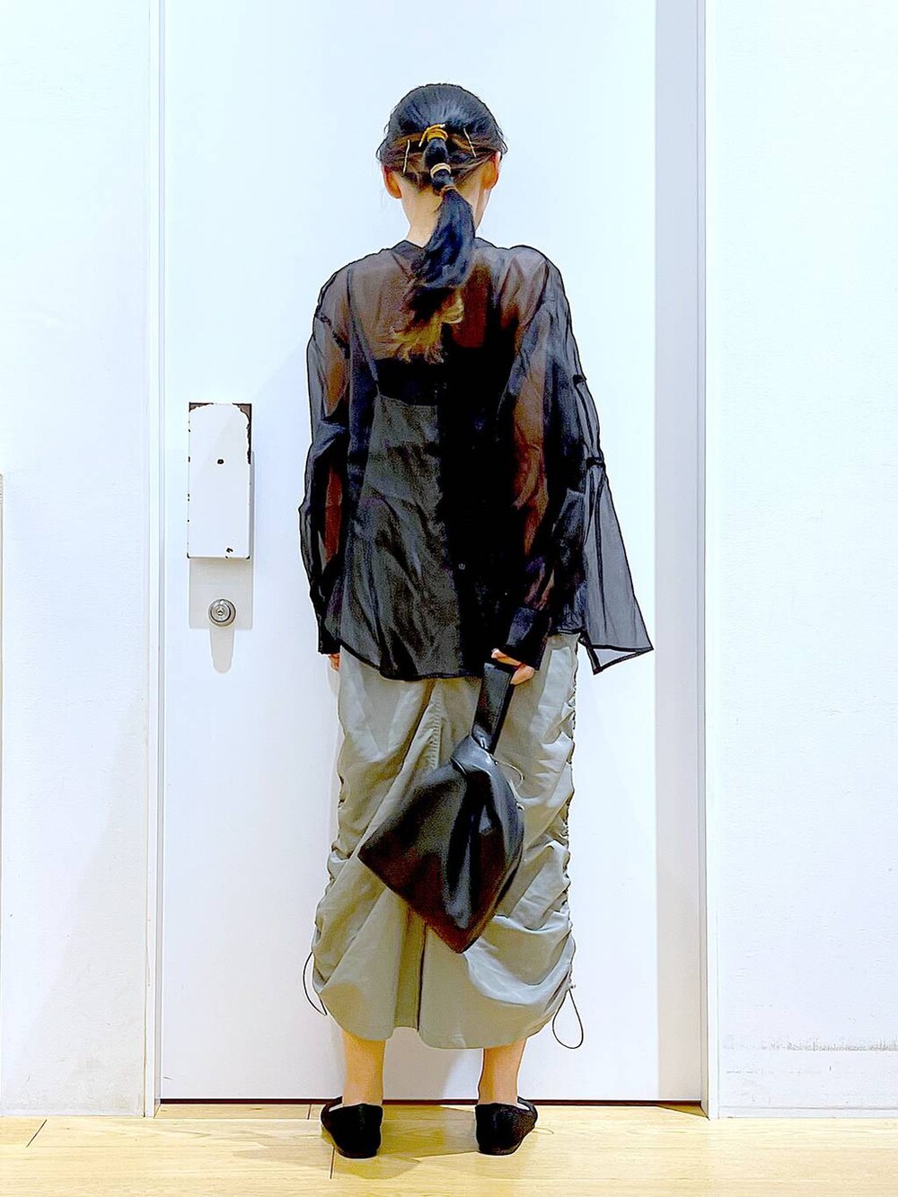 ブラック系のショルダーバッグ、ブラック系のパンプス、グリーン系のワンピースを着用したレディースの春コーディネートの5枚目の写真