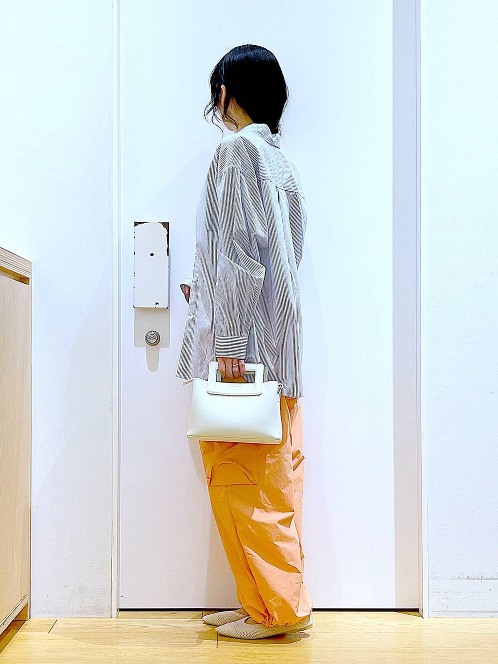 ホワイト系のシャツ/ブラウス、イエロー系のニット/セーター、ホワイト系のショルダーバッグを着用したレディースの春コーディネートの3枚目の写真