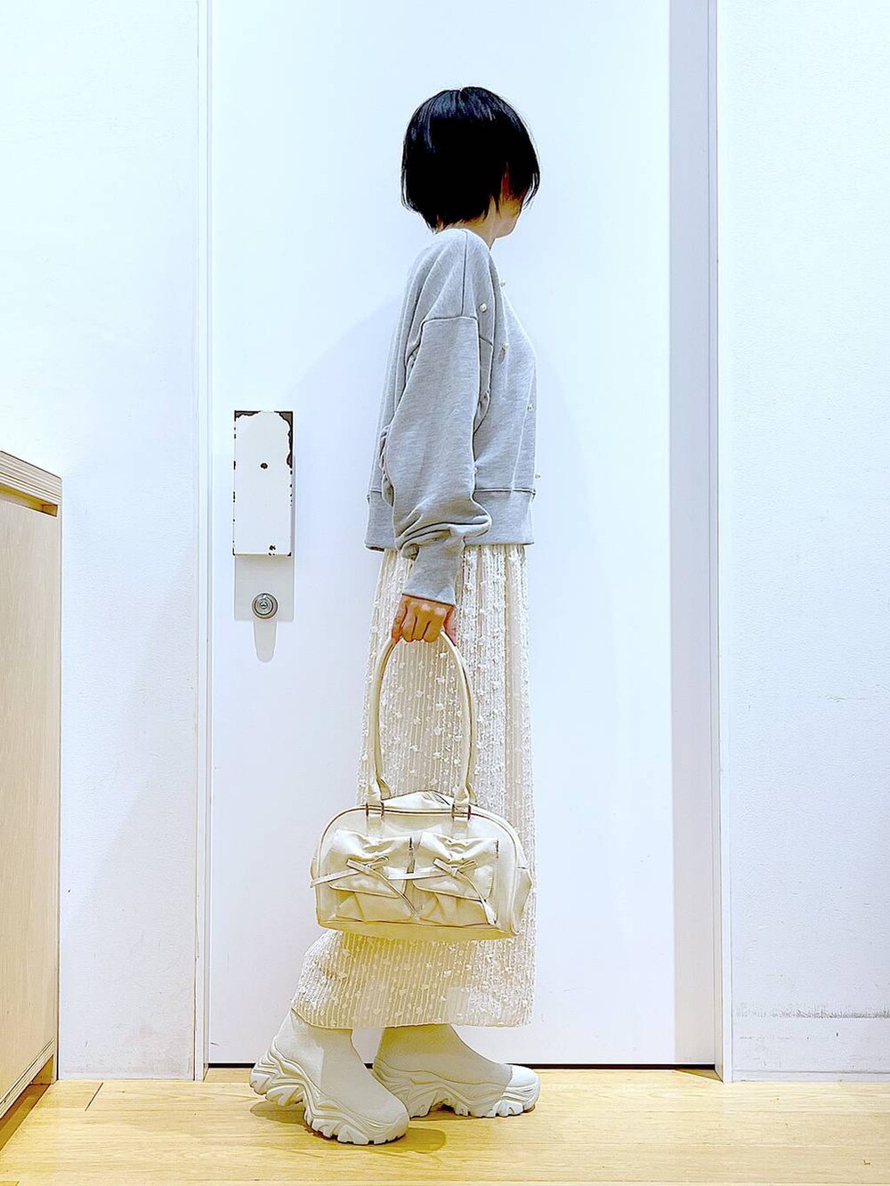 ホワイト系のハンドバッグ、グレー系のスウェット、ベージュ系のブーツを着用したレディースの秋コーディネートの4枚目の写真