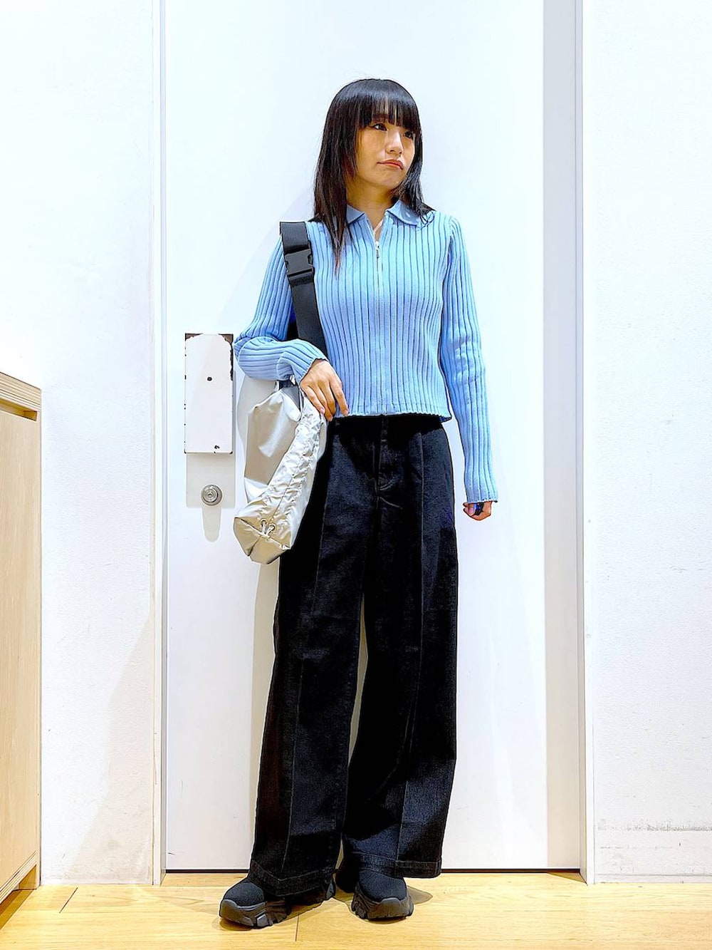 グレー系のデニムパンツ、ブルー系のカーディガン/ボレロ、ブラック系のブーツを着用したレディースの冬コーディネートの2枚目の写真