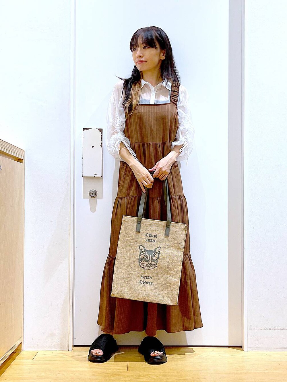 ブラック系のサンダル、ベージュ系のワンピース、グレー系のトートバッグを着用したレディースの夏コーディネートの2枚目の写真