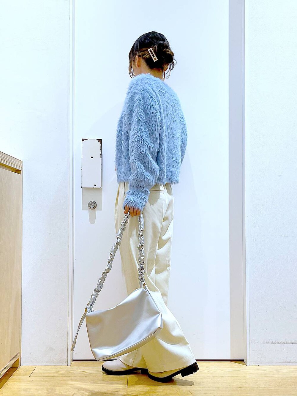 シルバー系のショルダーバッグ、ベージュ系のブーツ、ホワイト系のニット/セーターを着用したレディースの冬コーディネートの3枚目の写真