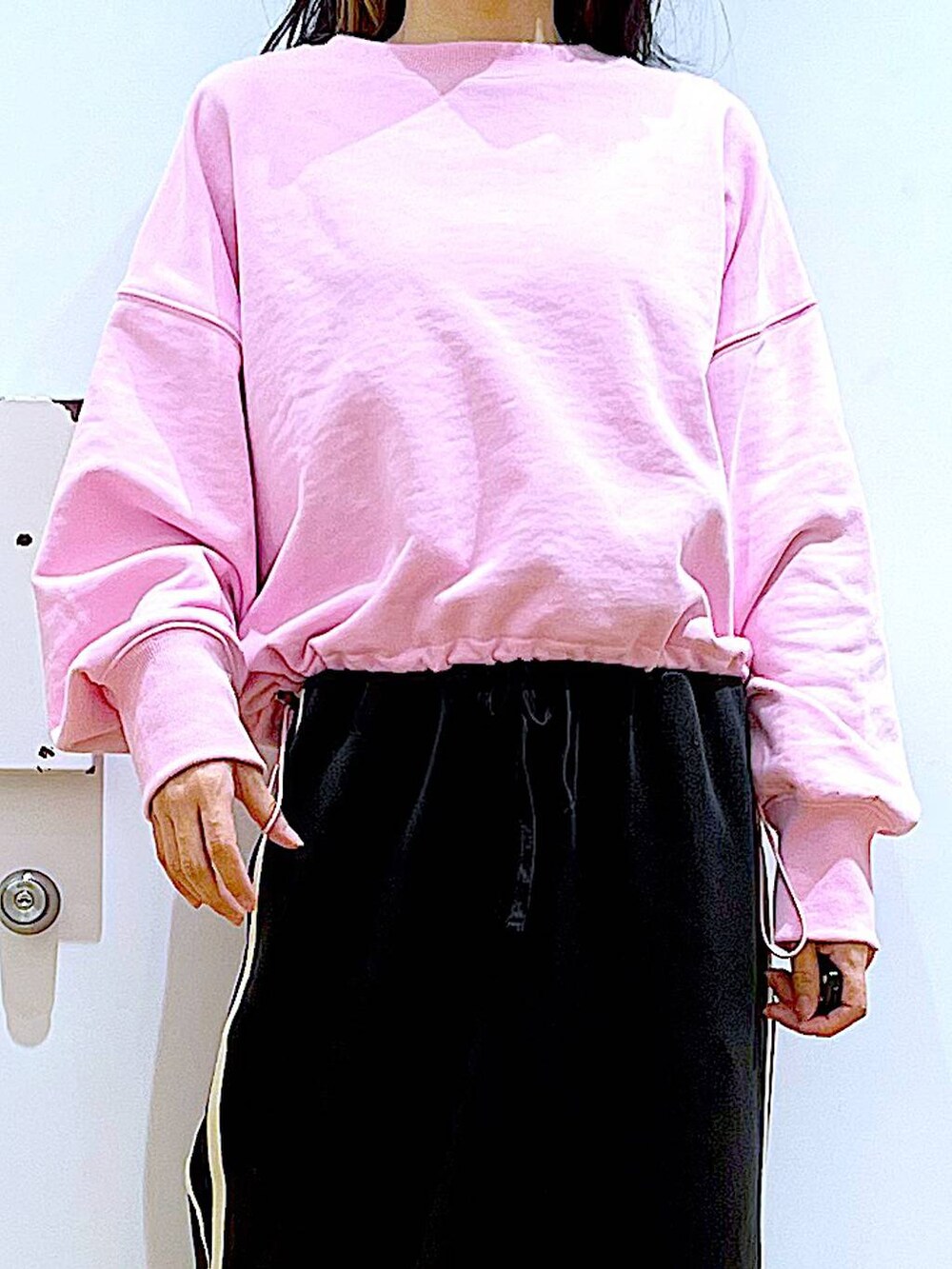 ピンク系のスウェット、ベージュ系のブーツ、ブラック系のショルダーバッグを着用したレディースの春コーディネートの7枚目の写真