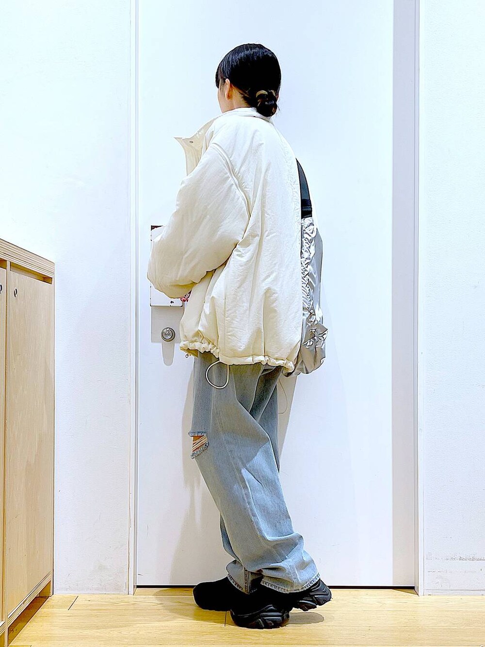 ブラック系のブーツ、ブルー系のデニムパンツ、シルバー系のショルダーバッグを着用したレディースの冬コーディネートの3枚目の写真