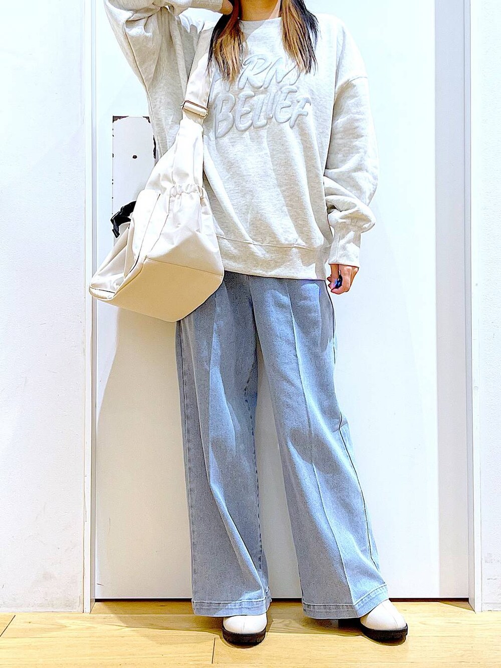 ブルー系のデニムパンツ、ベージュ系のスウェット、ベージュ系のブーツを着用したレディースの冬コーディネートの6枚目の写真