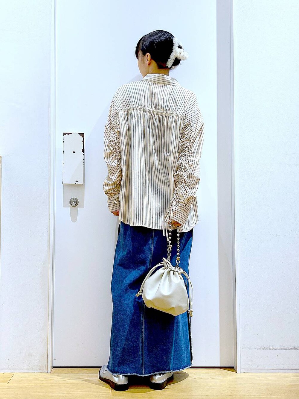 ベージュ系のショルダーバッグ、シルバー系のローファー、ブルー系のデニムスカートを着用したレディースの秋コーディネートの5枚目の写真