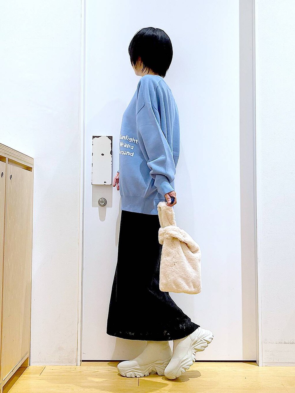 ブルー系のニット/セーター、ホワイト系のショルダーバッグ、ベージュ系のブーツを着用したレディースの冬コーディネートの3枚目の写真