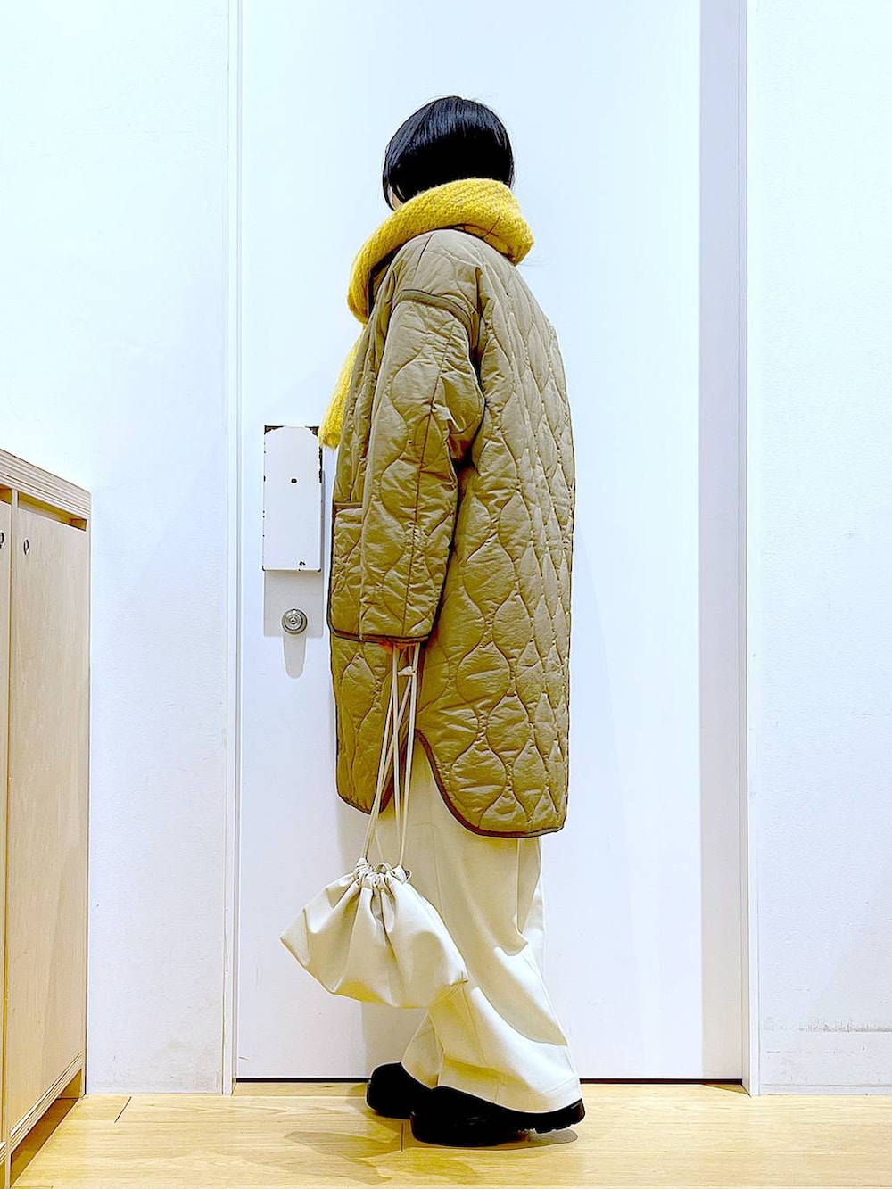 グリーン系のナイロンジャケット、ベージュ系のショルダーバッグ、ブラック系のブーツを着用したレディースの冬コーディネートの3枚目の写真