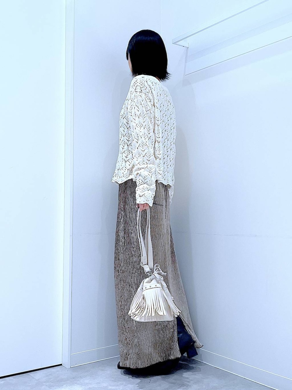 ブラック系のブーツ、ホワイト系のショルダーバッグ、ベージュ系のカーディガン/ボレロを着用したレディースの冬コーディネートの3枚目の写真