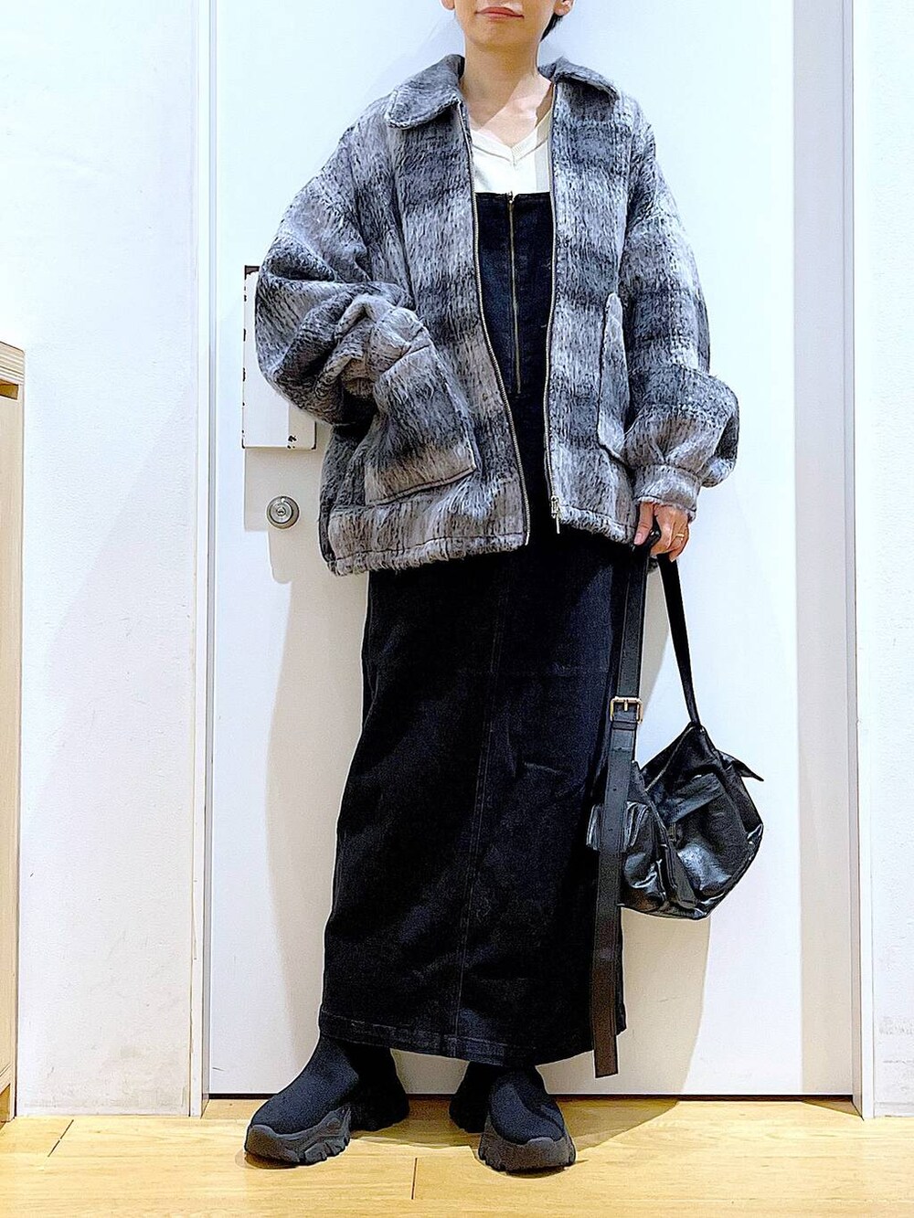 グレー系のジャンパースカート、ブラック系のブーツ、ブラック系のショルダーバッグを着用したレディースの冬コーディネートの6枚目の写真