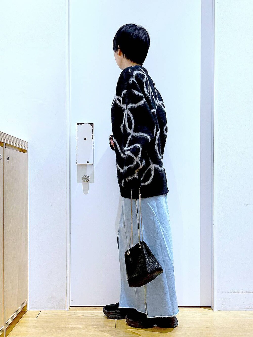 ブルー系のデニムスカート、ブラック系のブーツ、ブラック系のショルダーバッグを着用したレディースの冬コーディネートの3枚目の写真