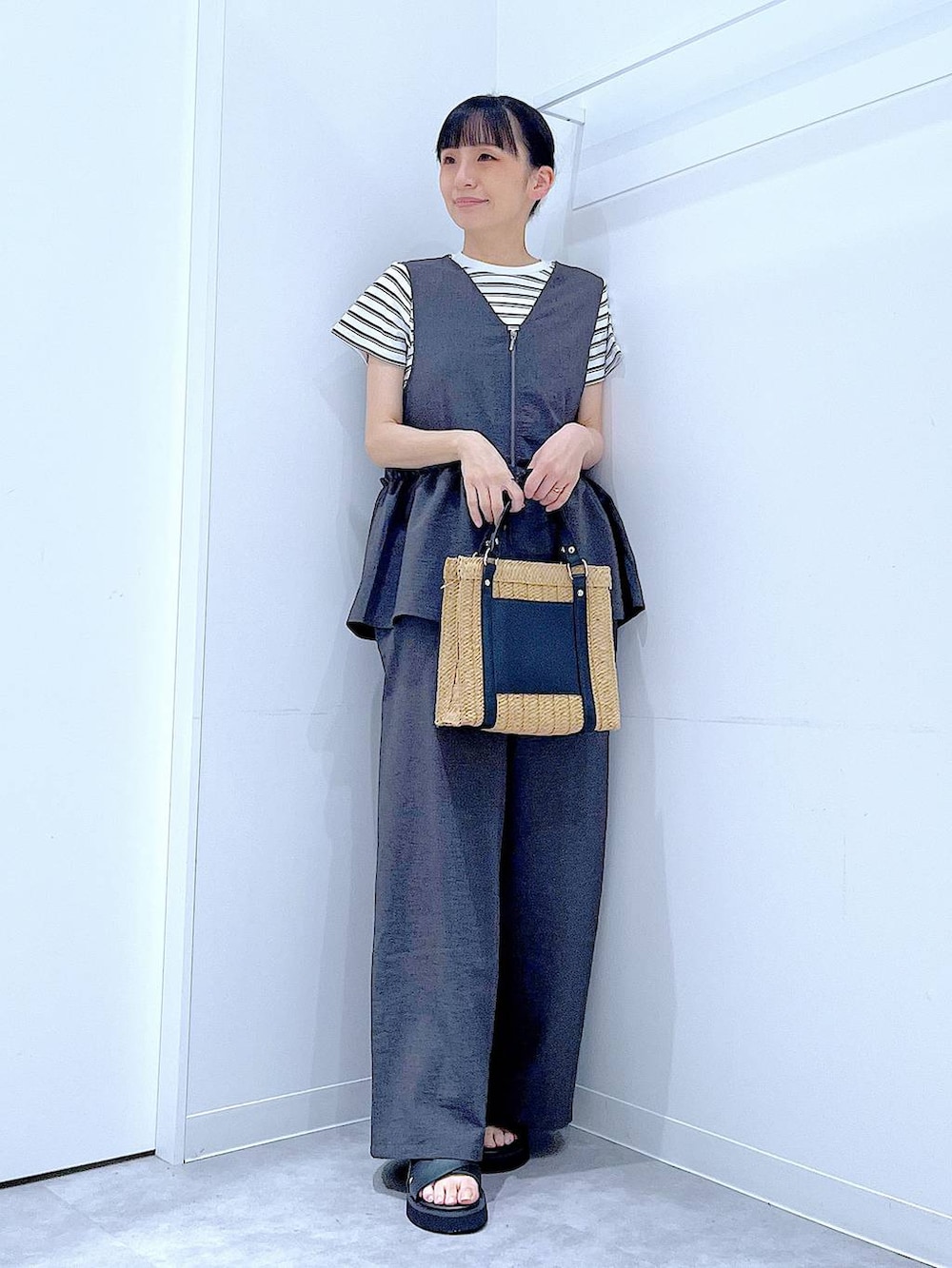 ベージュ系のショルダーバッグ、ブラック系のサンダル、ベージュ系のTシャツ/カットソーを着用したレディースの夏コーディネートの2枚目の写真