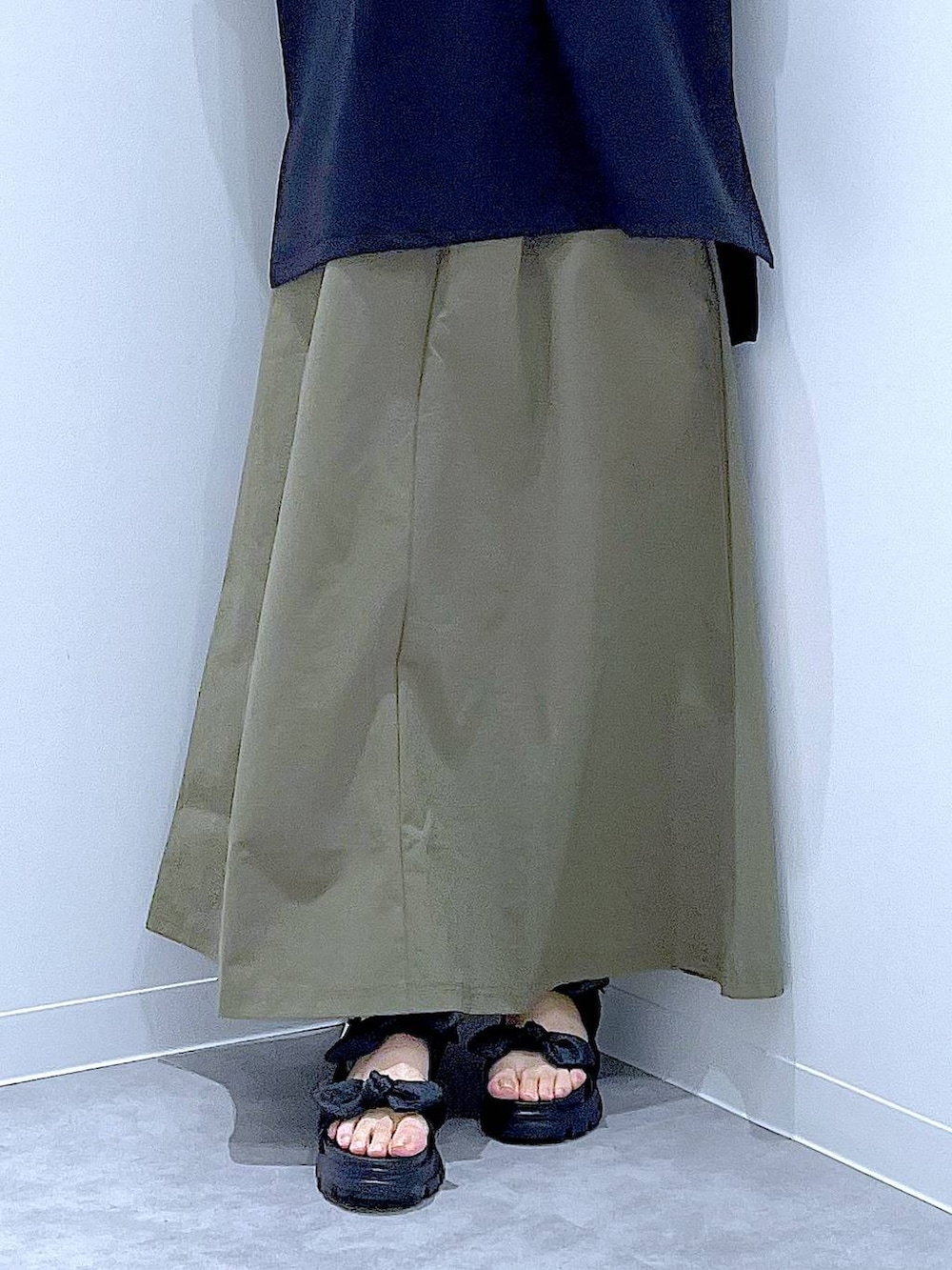 ブラック系のショルダーバッグ、ブラック系のサンダル、グリーン系のスカートを着用したレディースの夏コーディネートの8枚目の写真