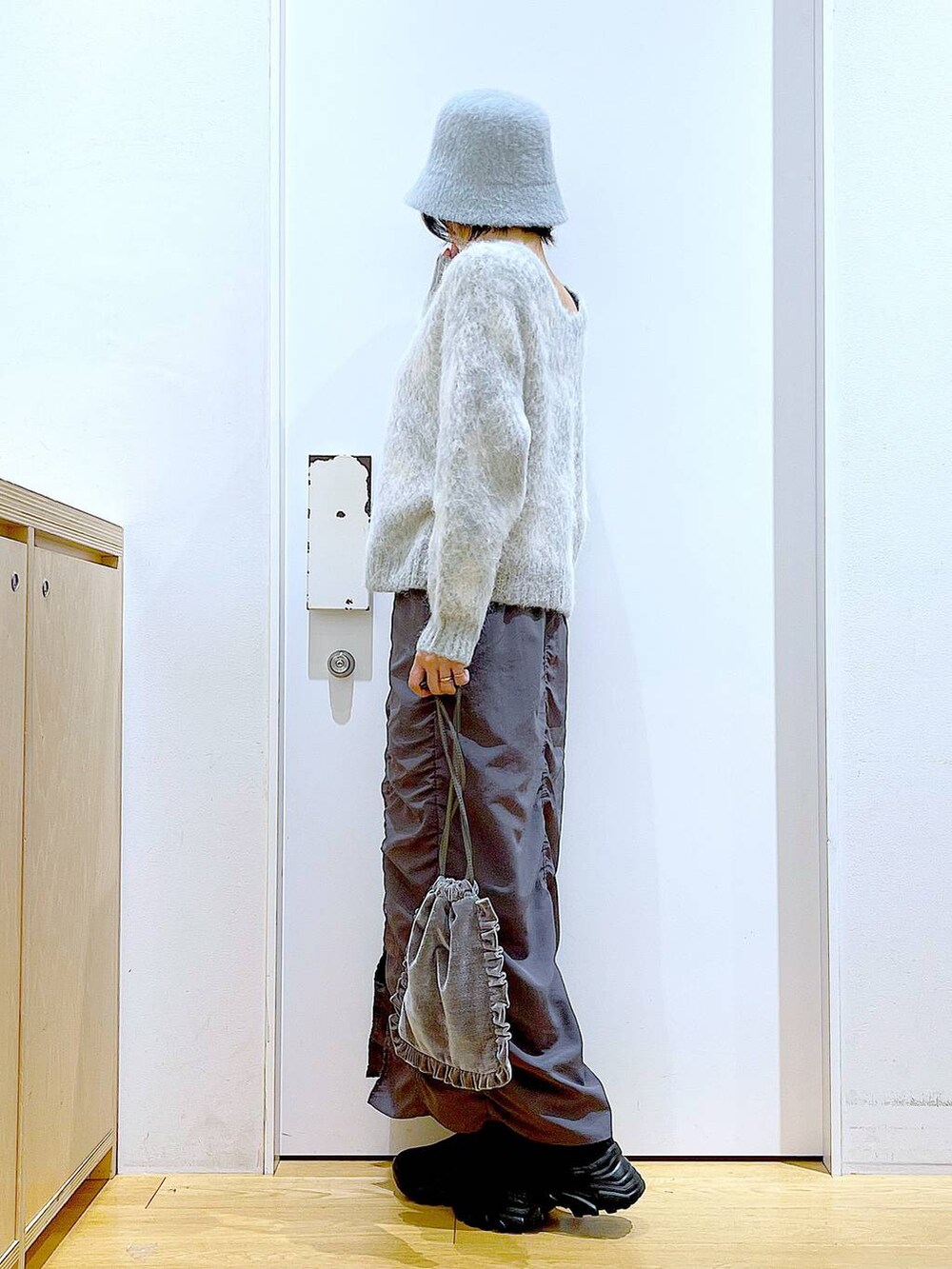 グレー系のショルダーバッグ、グレー系のスカート、ブラック系のブーツを着用したレディースの冬コーディネートの3枚目の写真