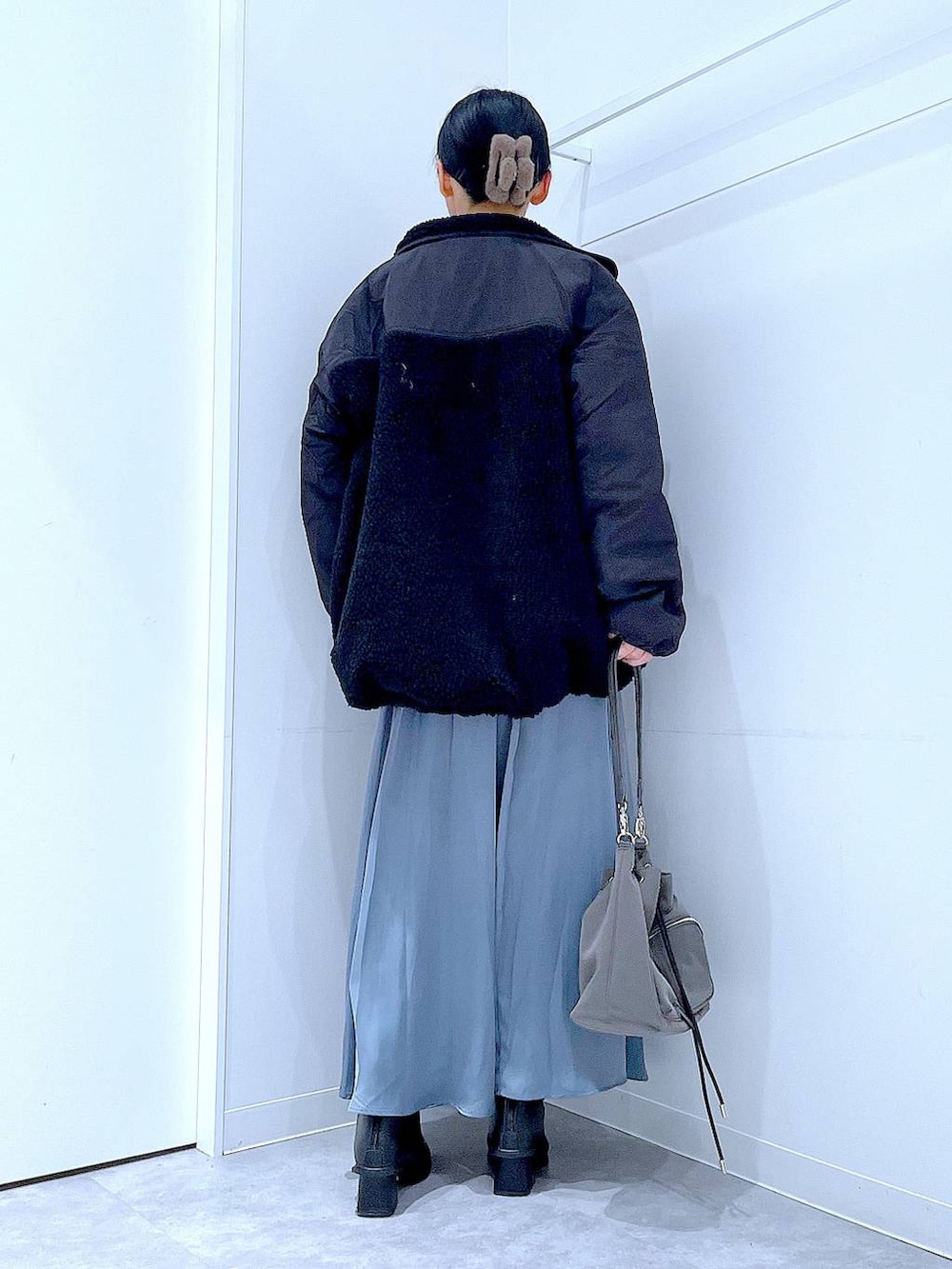 ブラック系のブルゾン、ブラック系のブーツ、ブルー系のスカートを着用したレディースの冬コーディネートの5枚目の写真