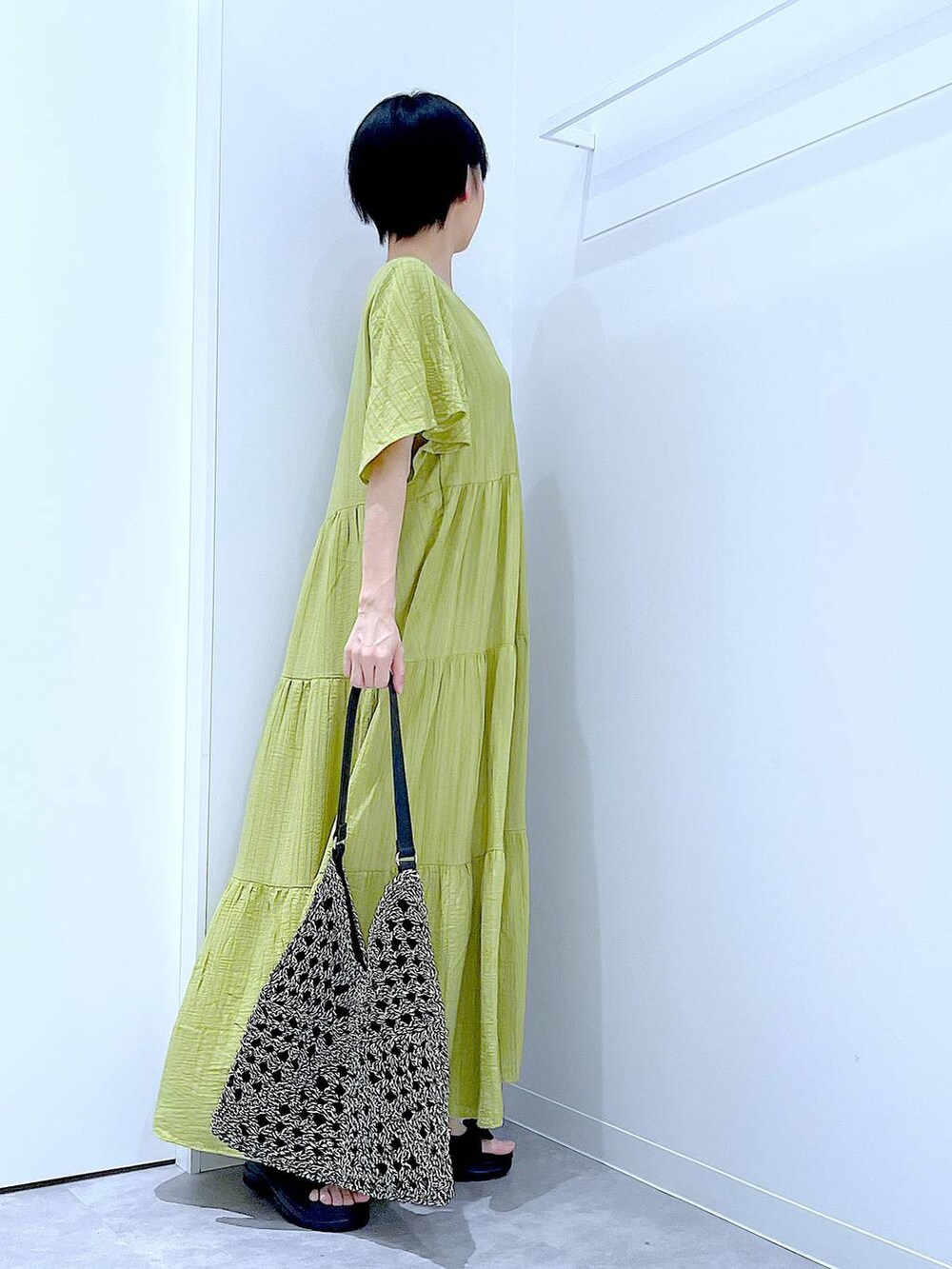 ブラック系のトートバッグ、ブラック系のサンダル、グリーン系のワンピースを着用したレディースの夏コーディネートの4枚目の写真