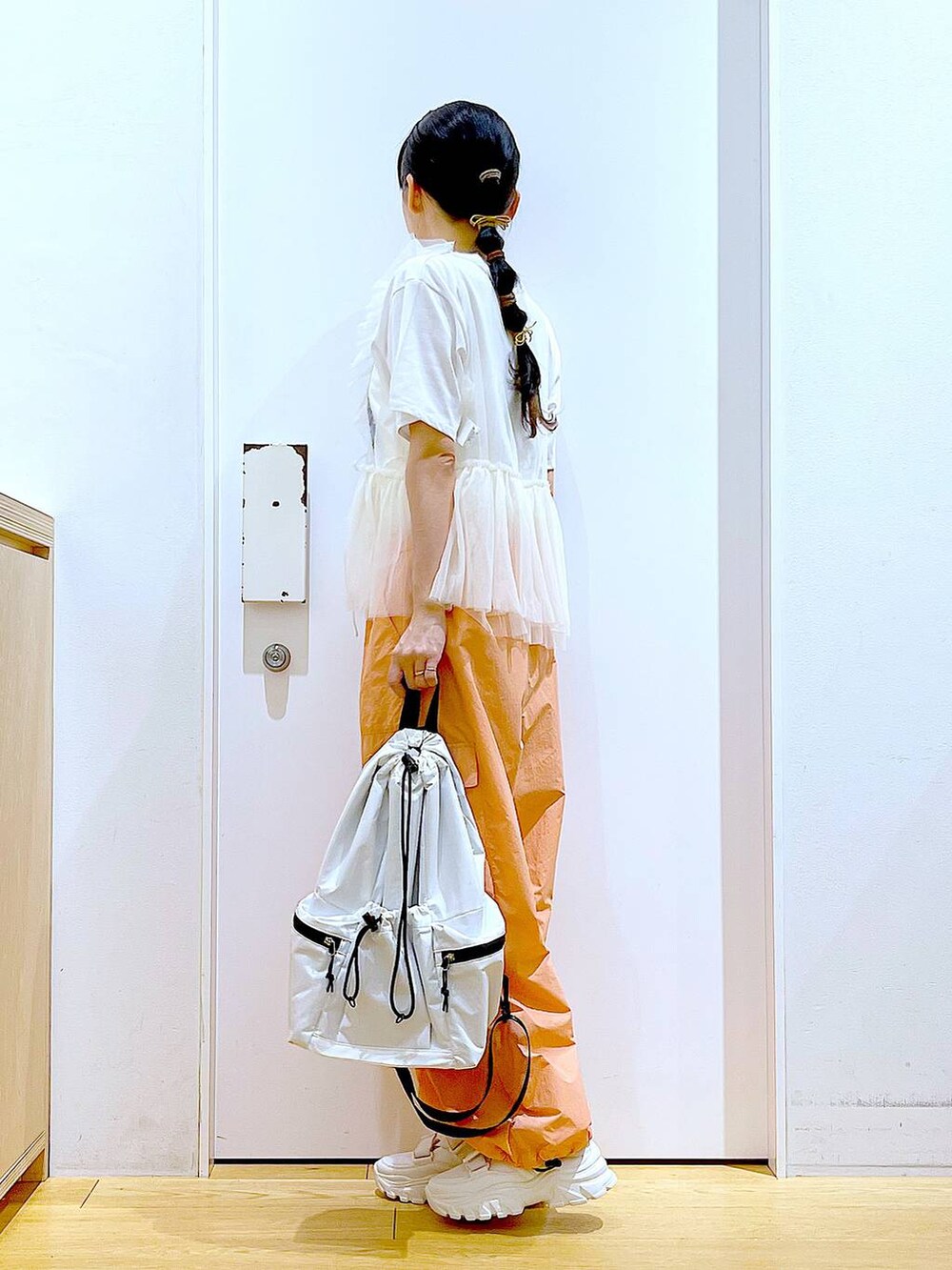 ホワイト系のスニーカー、ホワイト系のショルダーバッグ、オレンジ系のカーゴパンツを着用したレディースの夏コーディネートの3枚目の写真