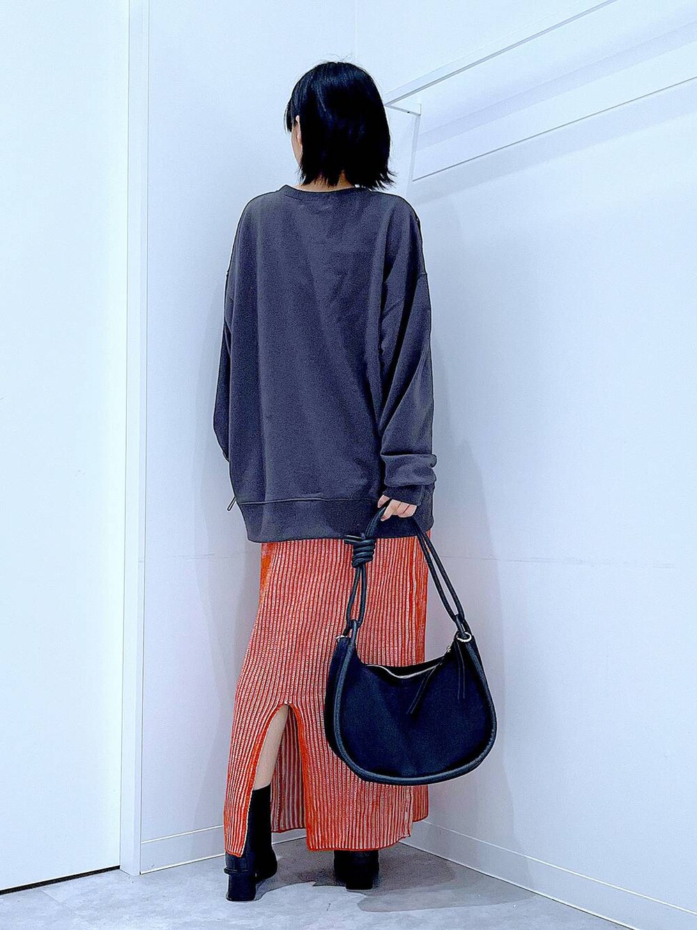 オレンジ系のスカート、ブラック系のブーツ、ブラック系のショルダーバッグを着用したレディースの秋コーディネートの5枚目の写真