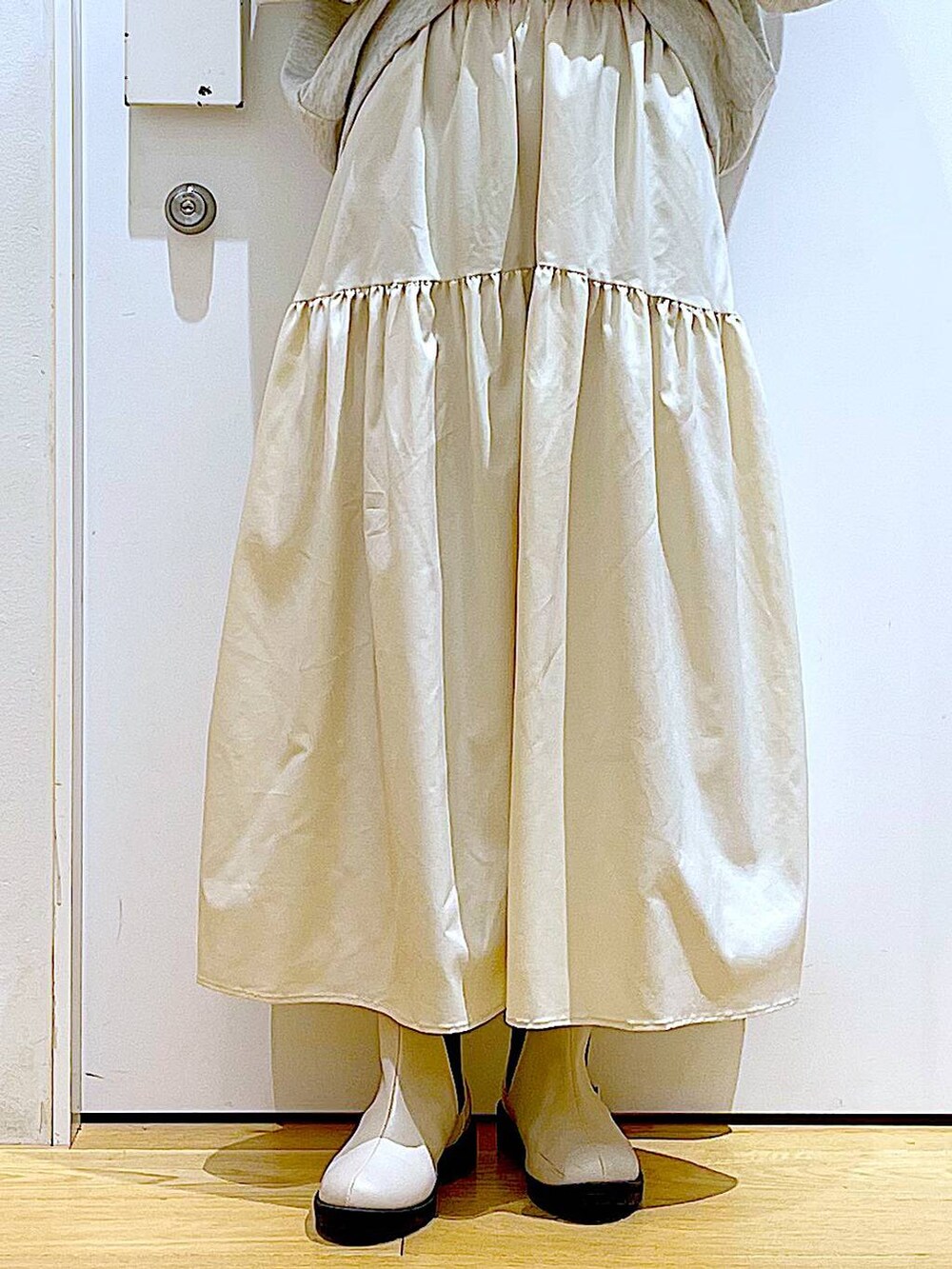 ベージュ系のスウェット、ホワイト系のスカート、ベージュ系のブーツを着用したレディースの春コーディネートの8枚目の写真