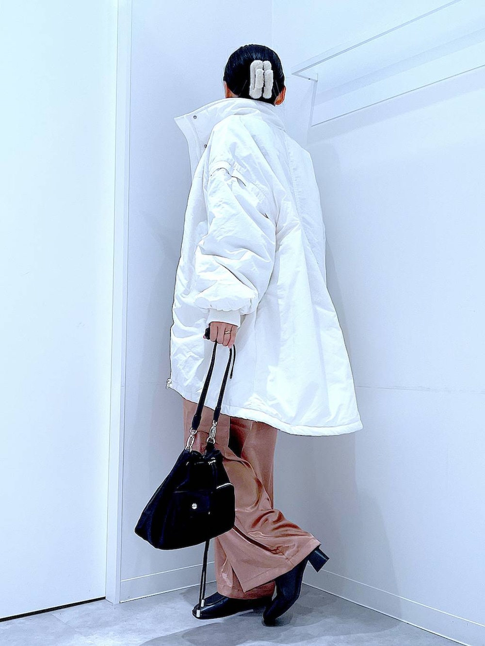 ホワイト系のブルゾン、ブラック系のショルダーバッグ、ブラック系のブーツを着用したレディースの冬コーディネートの3枚目の写真