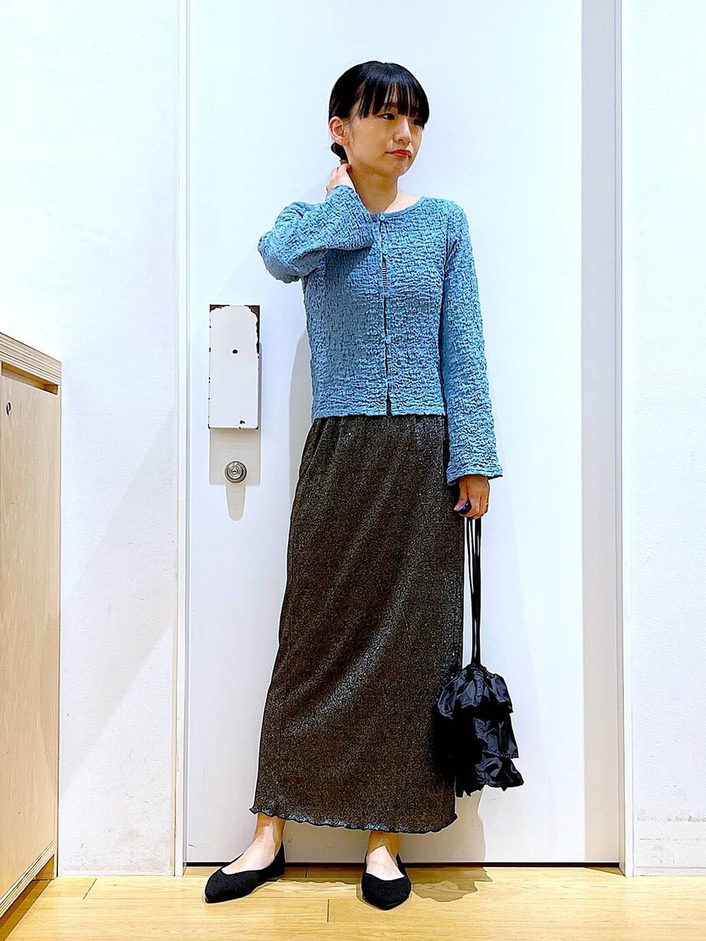 ブラック系のスカート、ブラック系のショルダーバッグ、ブラック系のパンプスを着用したレディースの春コーディネートの2枚目の写真