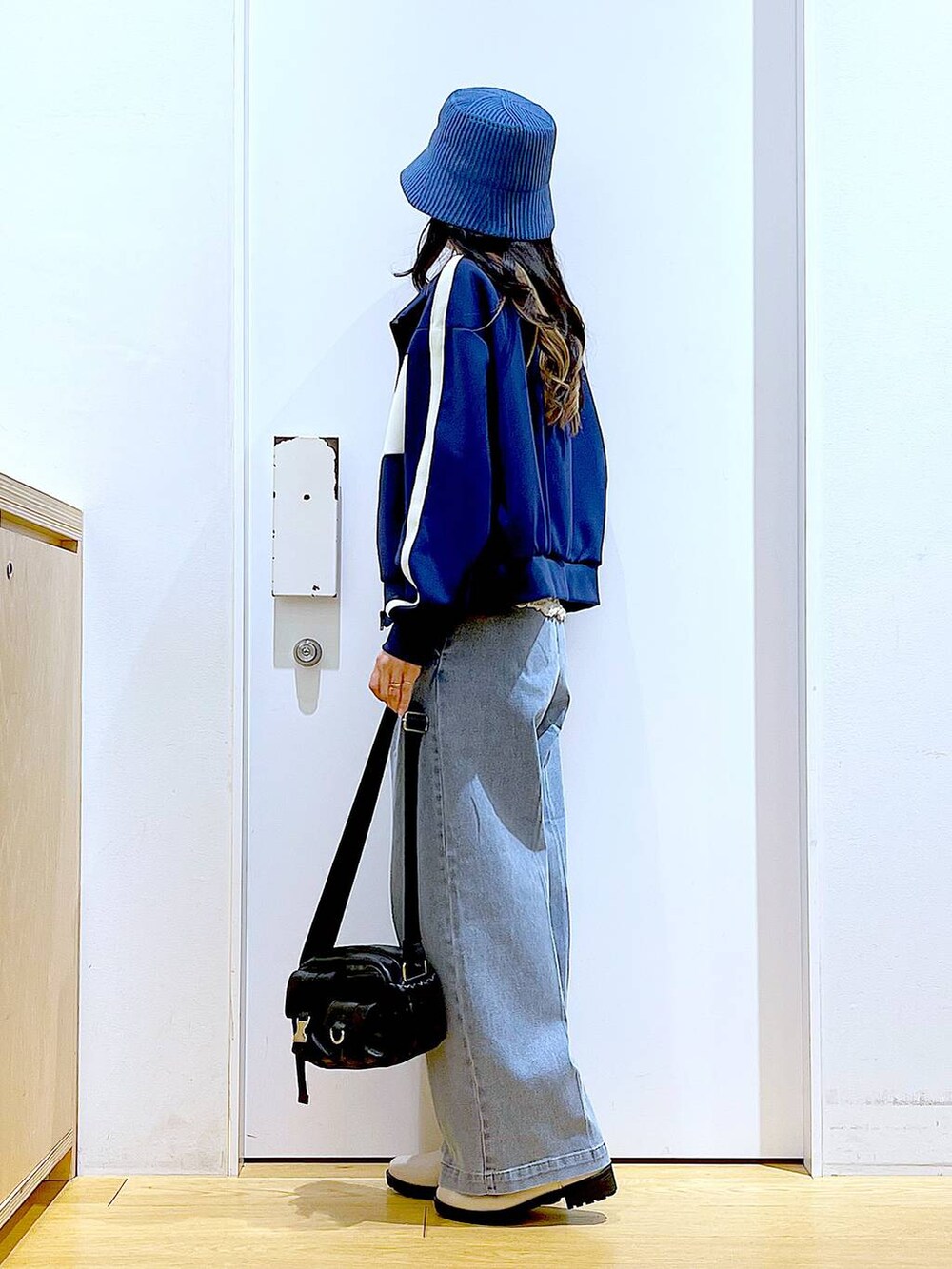 ブルー系のデニムパンツ、ベージュ系のブーツ、ブラック系のショルダーバッグを着用したレディースの冬コーディネートの3枚目の写真