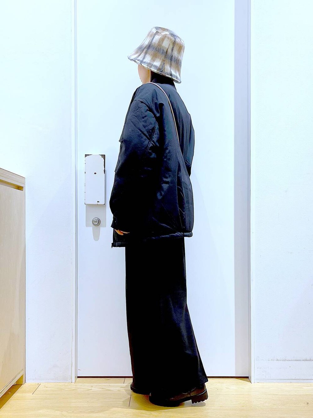 ブラック系のブルゾン、ブラック系のブーツ、ブラウン系のクラッチバッグを着用したレディースの冬コーディネートの3枚目の写真