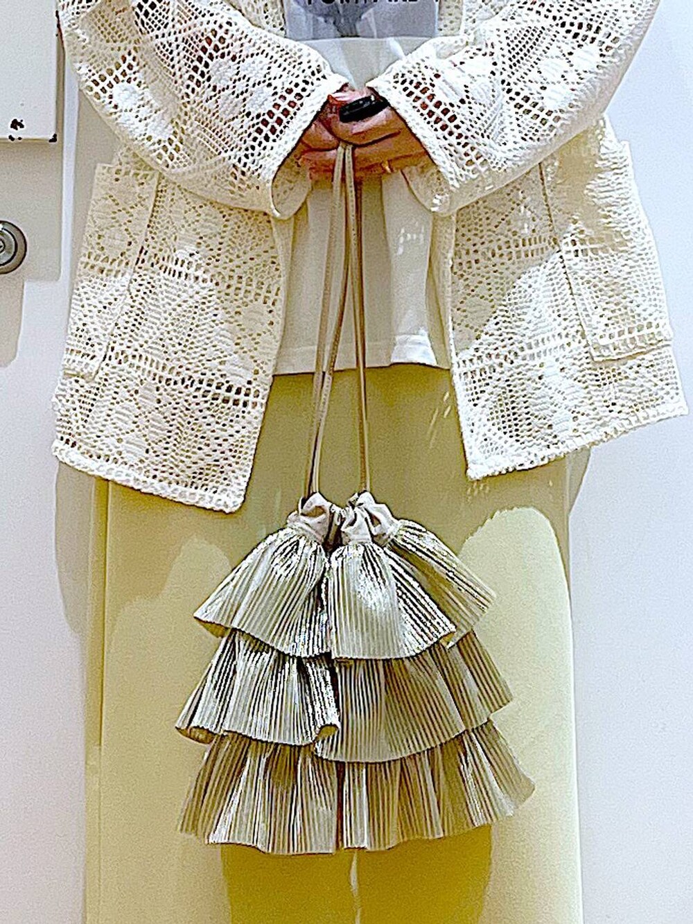 シルバー系のパンプス、ベージュ系のショルダーバッグ、イエロー系のスカートを着用したレディースの春コーディネートの9枚目の写真