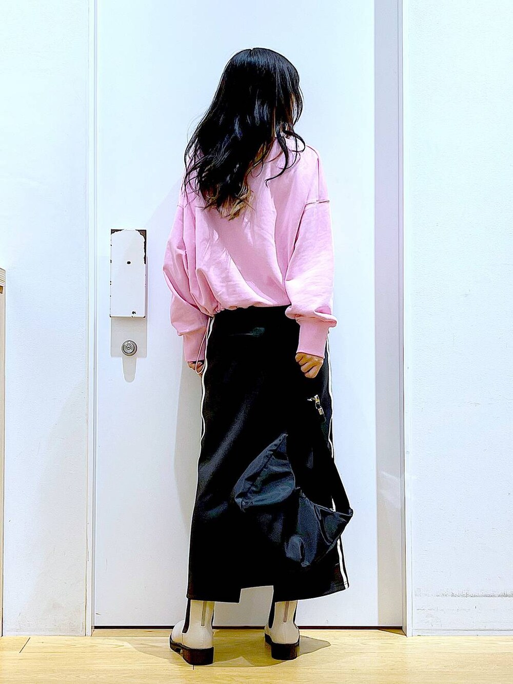 ピンク系のスウェット、ベージュ系のブーツ、ブラック系のショルダーバッグを着用したレディースの春コーディネートの5枚目の写真