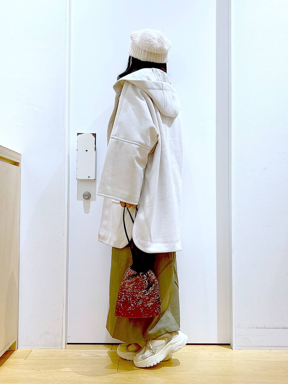 ホワイト系のその他アウター、ブラウン系のショルダーバッグ、ベージュ系のスニーカーを着用したレディースの冬コーディネートの3枚目の写真