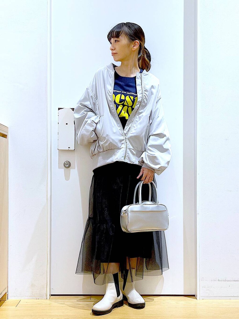 シルバー系のショルダーバッグ、グレー系のMA-1、ベージュ系のブーツを着用したレディースの春コーディネートの2枚目の写真