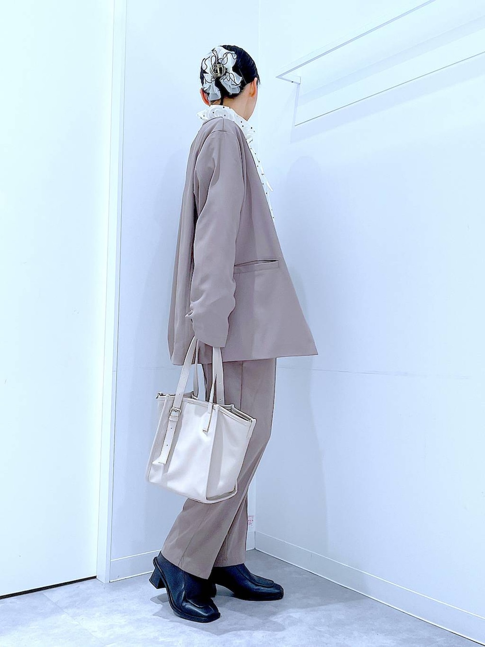 ブラック系のブーツ、グレー系のトートバッグ、ブラウン系のノーカラージャケットを着用したレディースの冬コーディネートの4枚目の写真