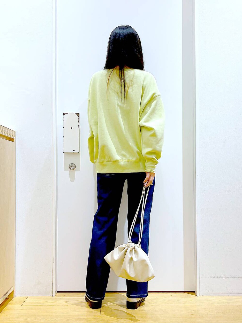 ブルー系のデニムパンツ、イエロー系のスウェット、ベージュ系のブーツを着用したレディースの冬コーディネートの5枚目の写真