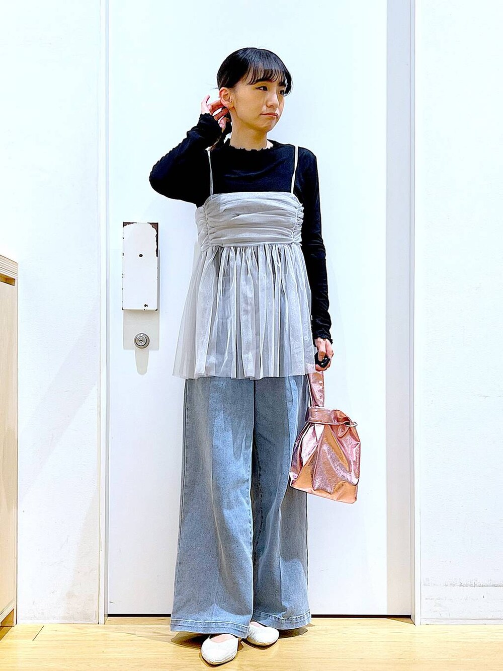 ブルー系のデニムパンツ、ピンク系のショルダーバッグ、ホワイト系のパンプスを着用したレディースの春コーディネートの2枚目の写真