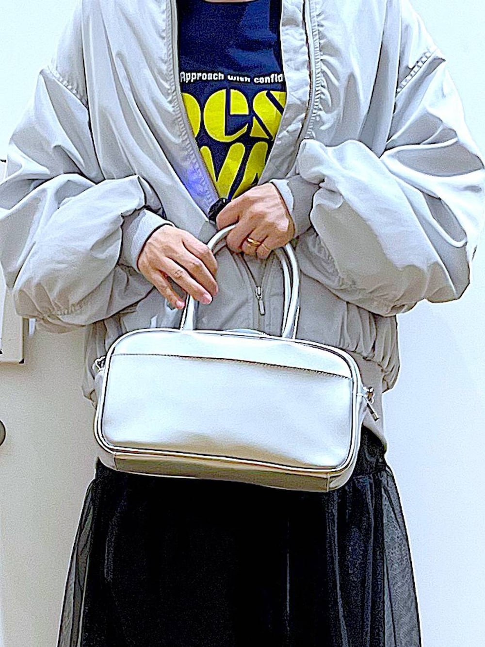 シルバー系のショルダーバッグ、グレー系のMA-1、ベージュ系のブーツを着用したレディースの春コーディネートの9枚目の写真