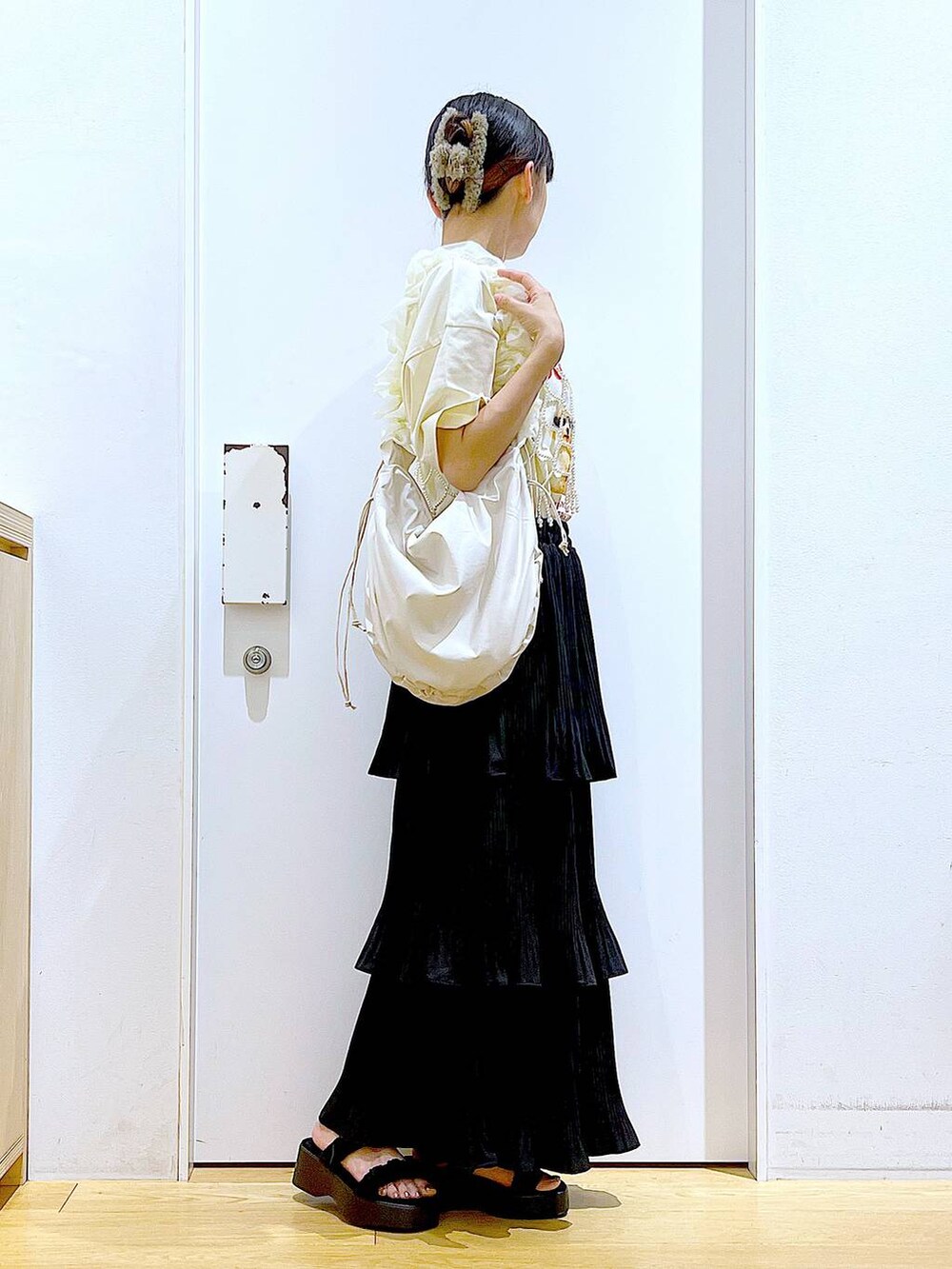 ブラック系のスカート、ブラック系のサンダル、ホワイト系のベストを着用したレディースの秋コーディネートの4枚目の写真