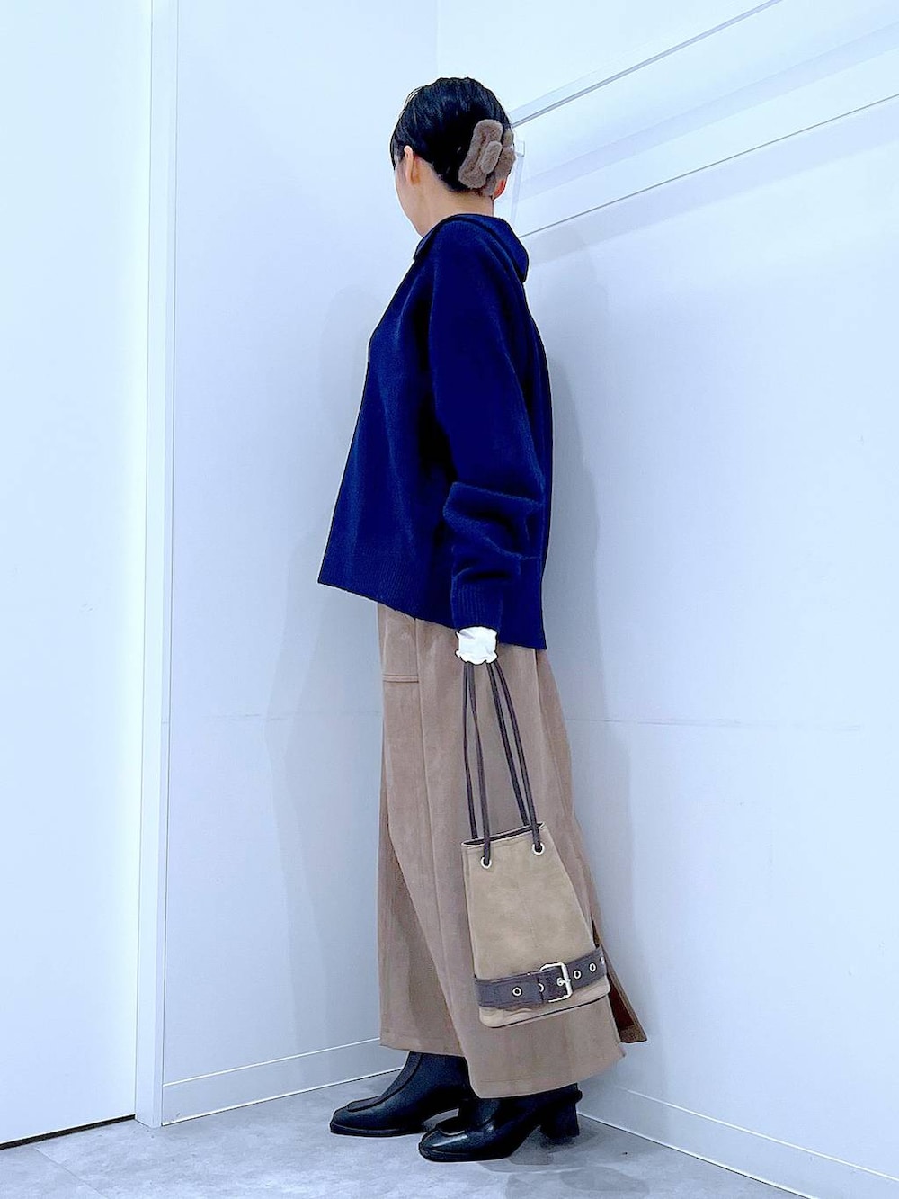 ブラック系のブーツ、ブラウン系のスカート、ベージュ系のハンドバッグを着用したレディースの冬コーディネートの3枚目の写真