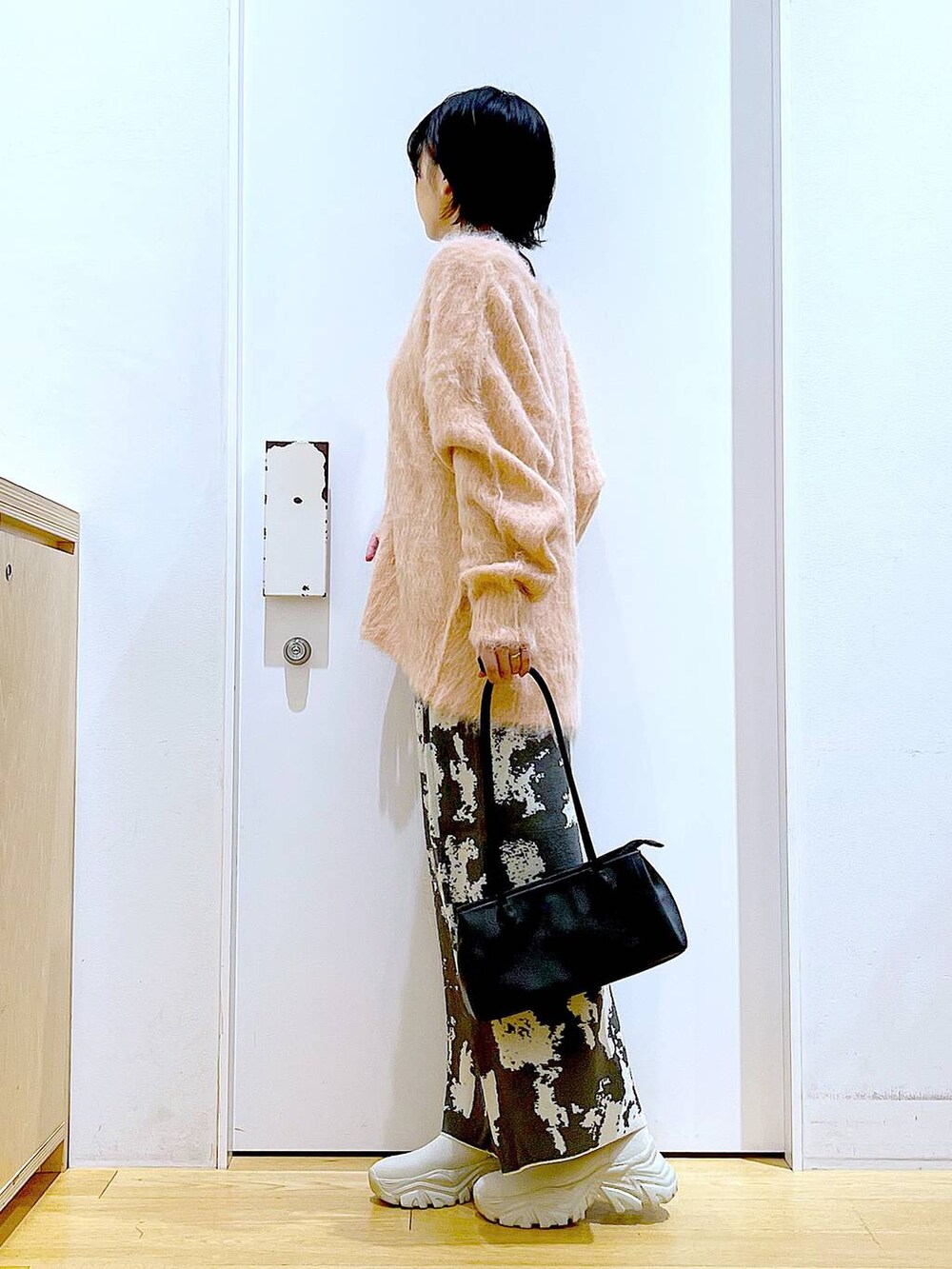 グレー系のスカート、ブラック系のトートバッグ、ピンク系のカーディガン/ボレロを着用したレディースの秋コーディネートの3枚目の写真